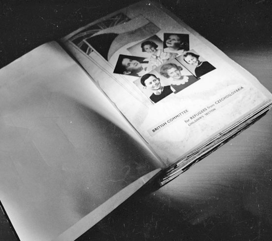 a scrapbook open on the first page and showing photographs of six of the evacuated children
